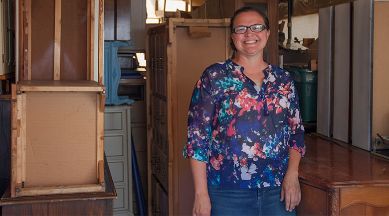Angela Ritchey, owner of Time and Again Furniture poses in her workshop with pieces of furniture that will soon become works of art.